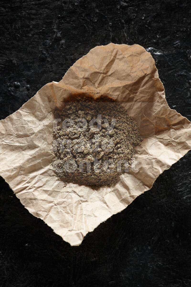 بودرة الهيل في قطعة من الورق على خلفية سوداء