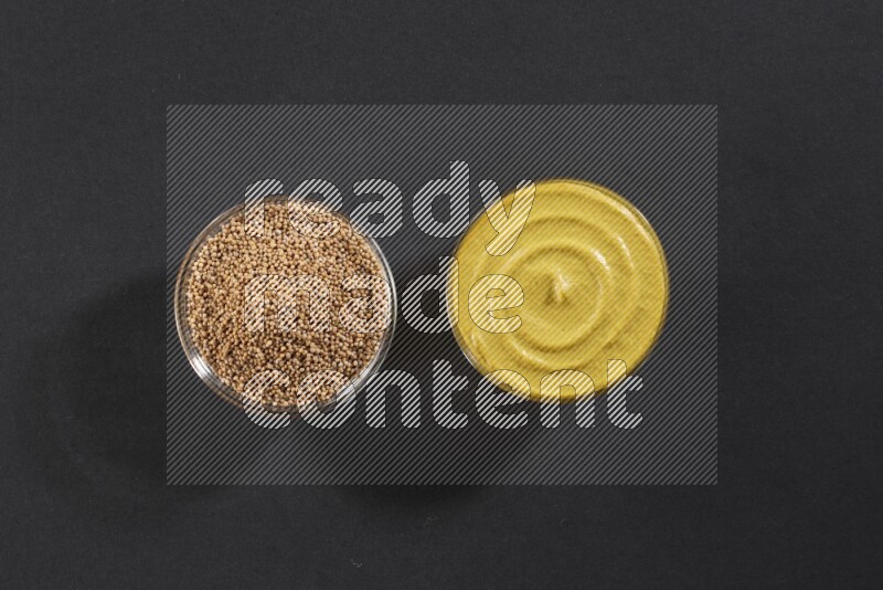 2 glass bowls, one full of mustard seeds and the other full of mustard paste on black flooring
