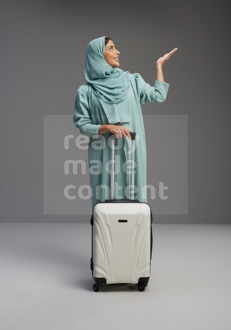 Saudi Woman wearing Abaya standing holding Travel bag on Gray background