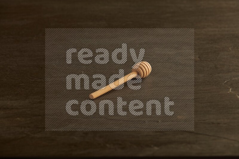 Wooden honey dipper on black slate background