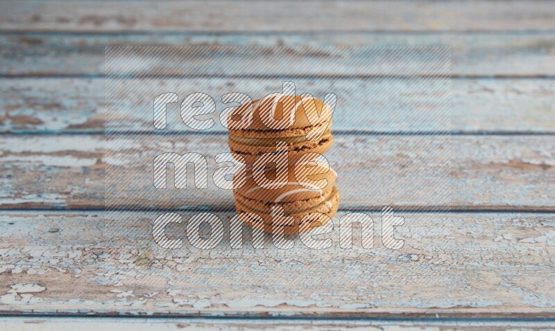 45º Shot of two Brown Irish Cream macarons on a  light blue wooden background