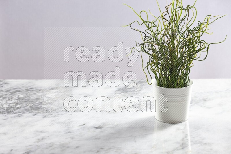 Green artificial plant in white pot on light grey marble background