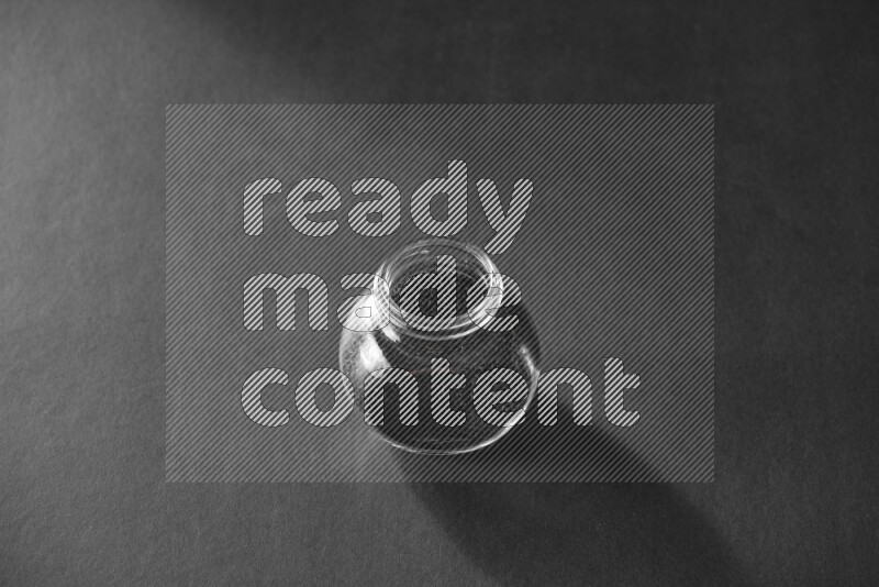 A glass spice jar full of black seeds on black flooring