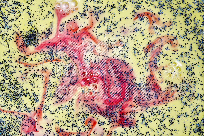 A close-up of sparkling blue glitter scattered on swirling yellow and red background