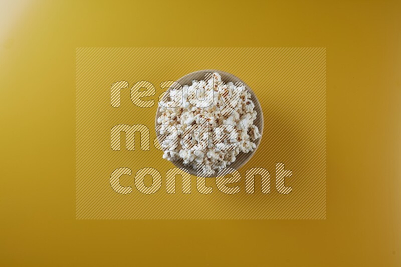 A multicolored ceramic plate full of popcorn on a yellow background in different angles