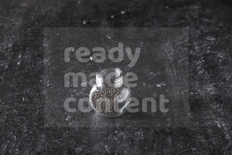 حبوب الفلفل الأسود في وعاء زجاجي علي خلفية سوداء