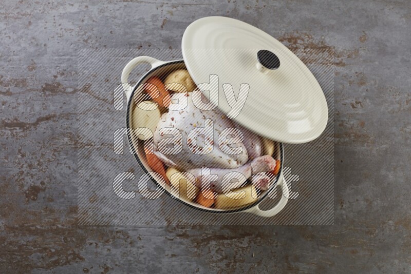 whole raw chicken on in a white ceramic pot direct on a rustic grey background