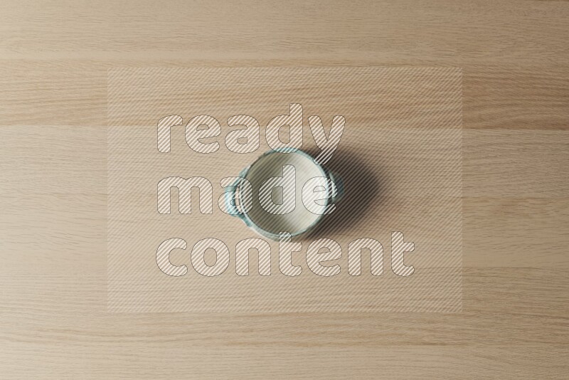 A multicolored pottery bowl on light wooden background