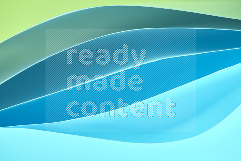 هذه الصورة تعرض تكوين فن الورق التجريدي مع منحنيات ورقية بتدرجات اللون الأخضر والأزرق المكونه بواسطة الضوء الملون