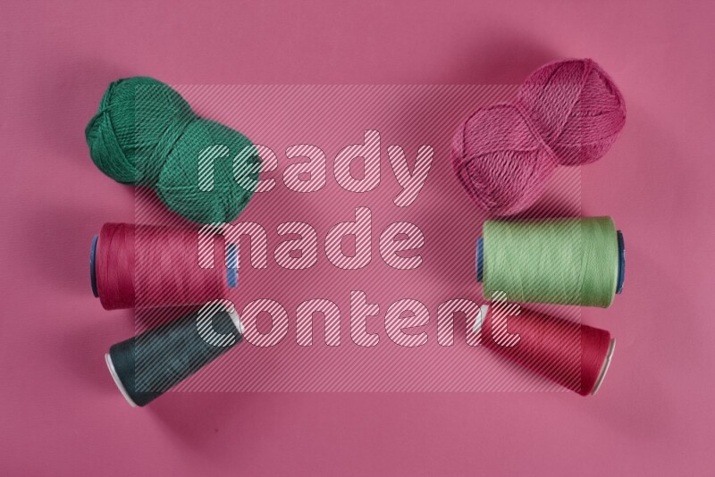 A green and pink collection of sewing and tailoring tools arranged on a pink background
