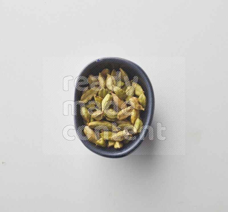 Top-view shot of Cardamon in a container on white background