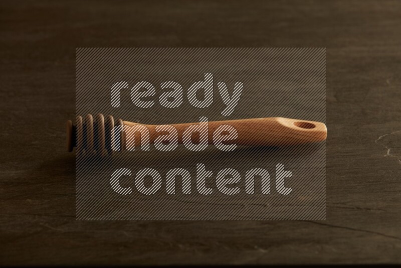 Wooden honey dipper on black slate background