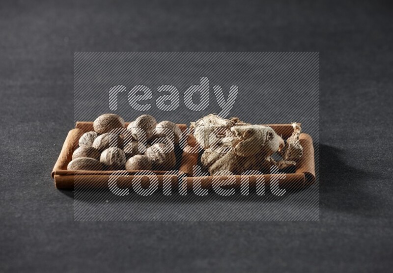 2 squares of cinnamon sticks full of nutmeg and dried ginger on black flooring