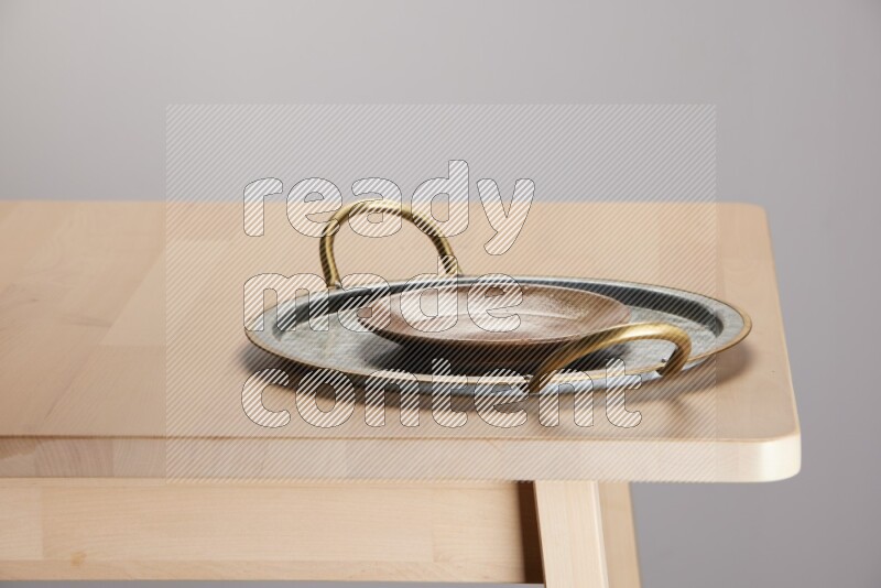 multicolored plate placed on a rounded stainless steel tray with golden handels on the edge of wooden table