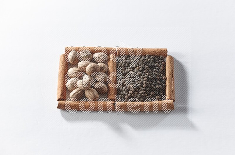 2 squares of cinnamon sticks full of black pepper and nutmegs on white flooring