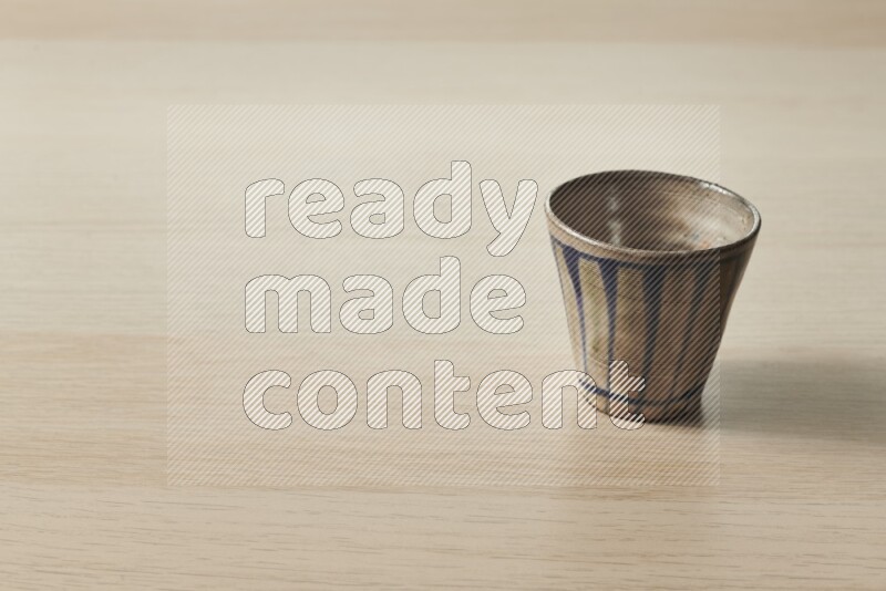 A pottery cup on light wooden background