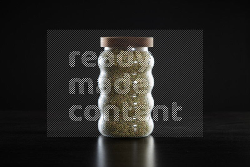 Freekeh in a glass jar on black background