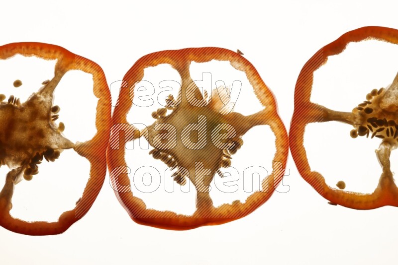 Red bell pepper slices on illuminated white background