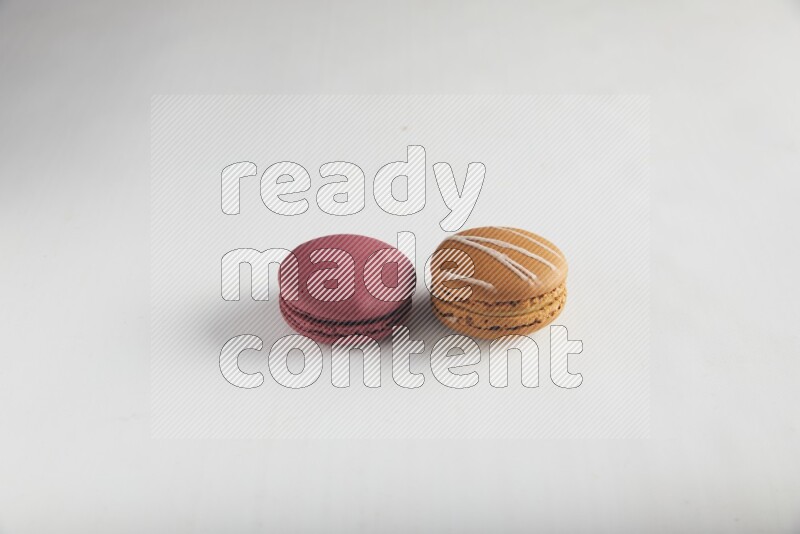 45º Shot of of two assorted Brown Irish Cream, and Red Cherry macarons on white background