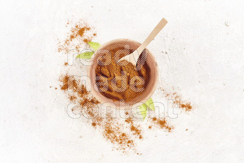 A wooden bowl full of ground paprika powder on white background