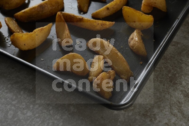 wedges potato in a black stainless steel rectangle tray on grey textured counter top