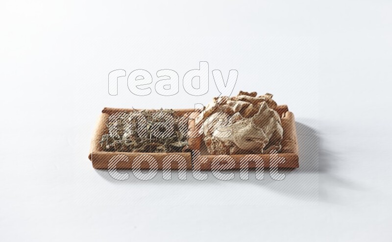 2 squares of cinnamon sticks full of dried ginger and dried basil on white flooring