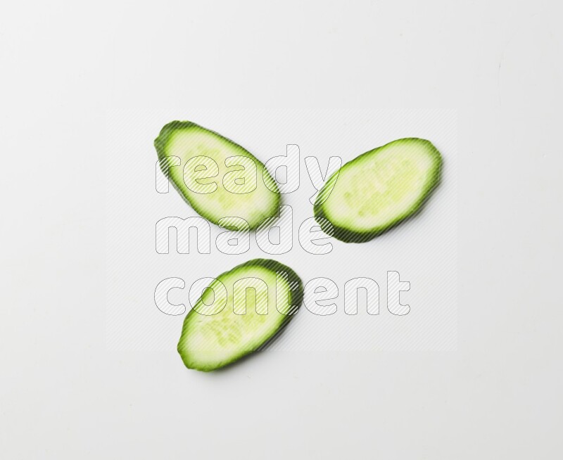 three cucumber slices on white background