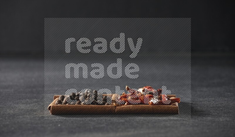 2 squares of cinnamon sticks full of chilis and allspice on black flooring