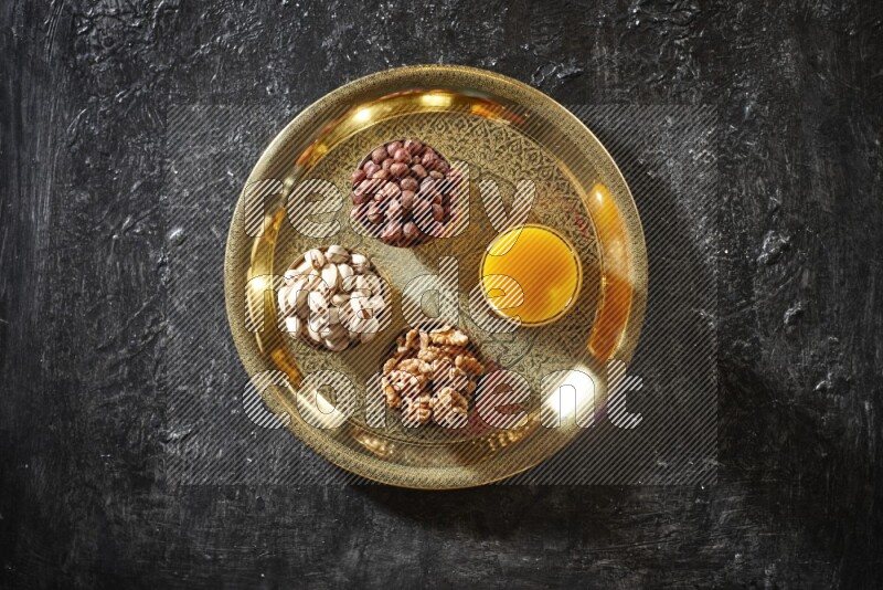 مكسرات في أطباق معدنية مع مشروب قمر الدين على صينية علي خلفية سوداء