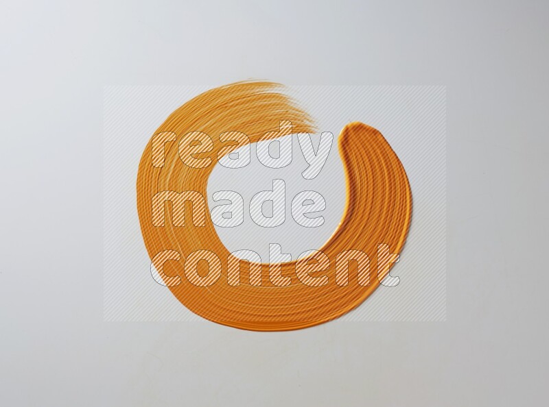 An orange circular painting brush stroke on white background