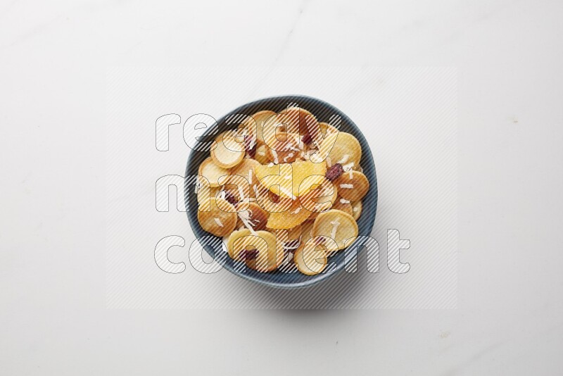 Top-view shot of orange candy cereal pancakes in a round bowl on white background