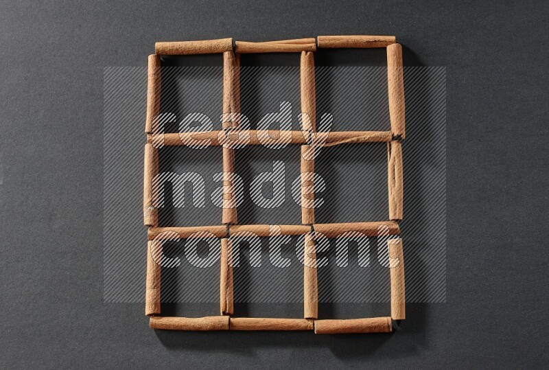 9 empty squares of cinnamon sticks on black flooring