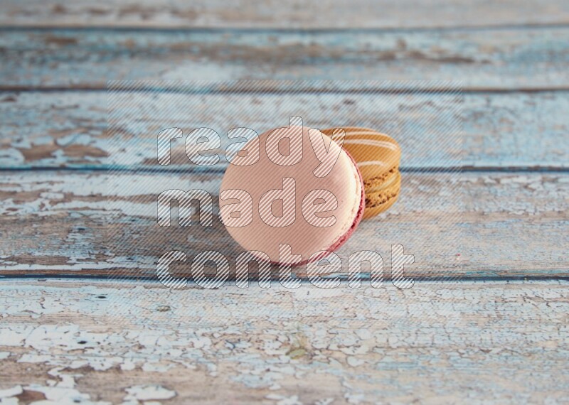 45º Shot of of two assorted Brown Irish Cream, and Pink Litchi Raspberry macarons on light blue background