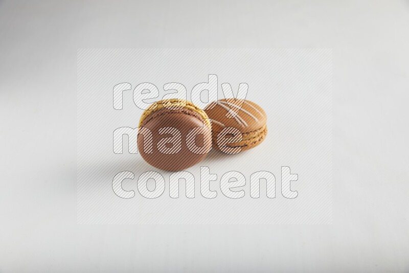 45º Shot of of two assorted Brown Irish Cream, and Yellow, and Brown Chai Latte macarons on white background
