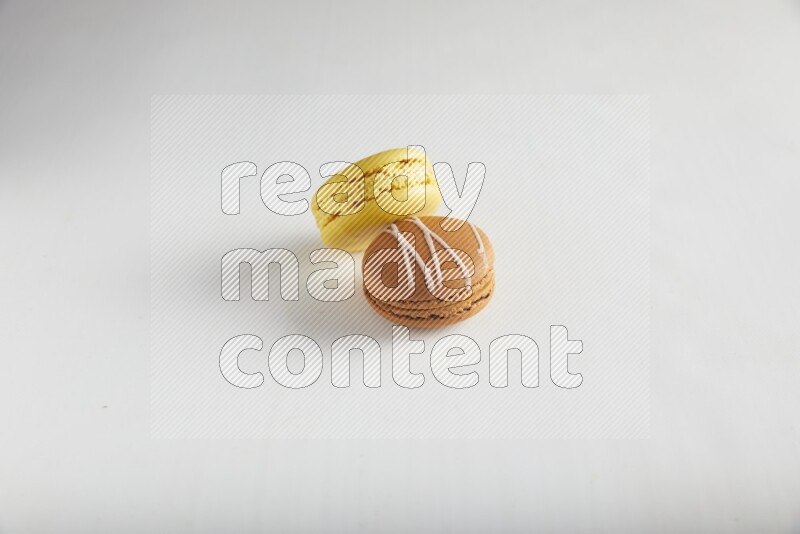 45º Shot of of two assorted Brown Irish Cream, and Yellow Lemon macarons on white background