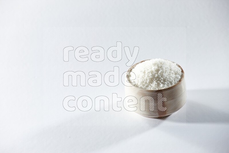 A beige ceramic bowl full of desiccated coconut on a white background in different angles
