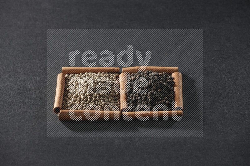 2 squares of cinnamon sticks full of white peppers and black peppers on black flooring