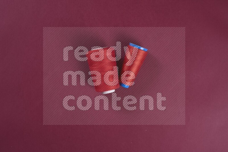 مجموعة من أدوات الخياطة والتفصيل حمراء اللون على خلفية حمراء