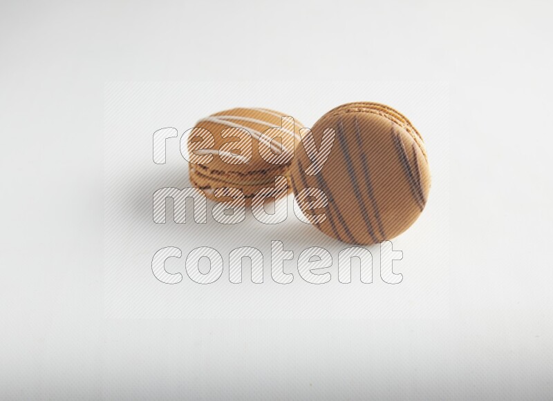 45º Shot of of two assorted Brown Irish Cream, and light brown  Almond Cream macarons on white background