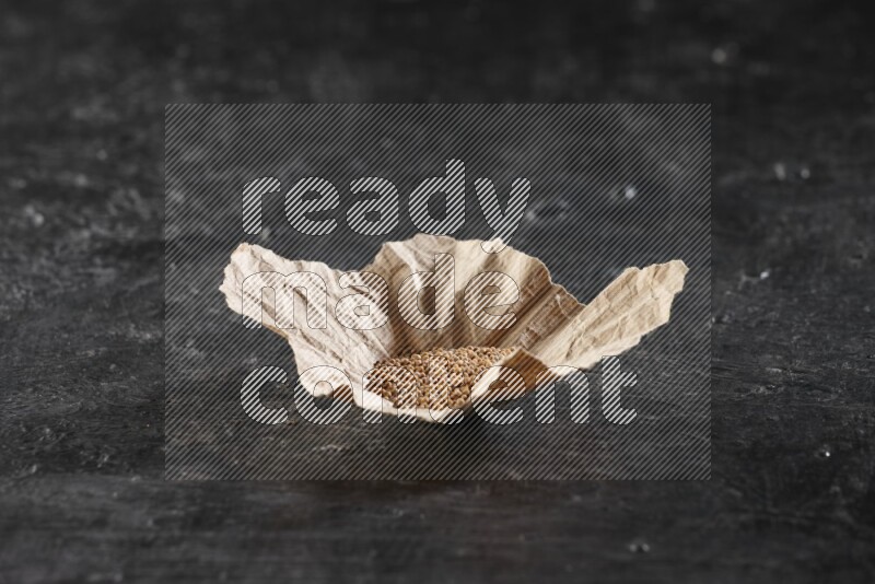 قطعة من الورق المجعد ممتلئة ببذور الخردل علي خلفية سوداء