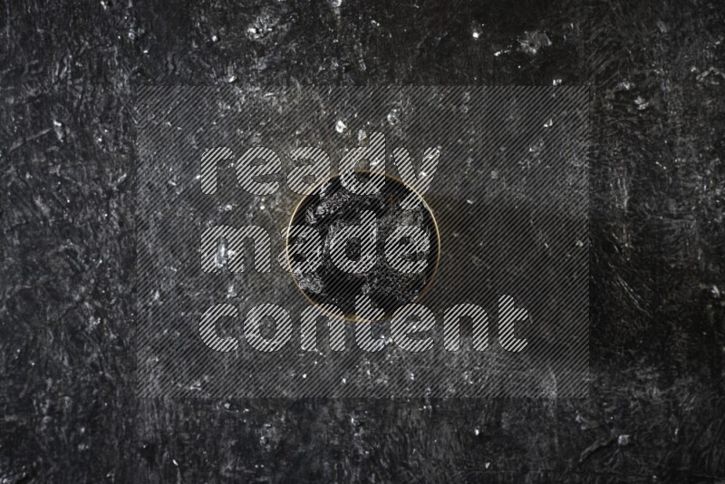 Dried fruits in a metal bowl in a dark setup