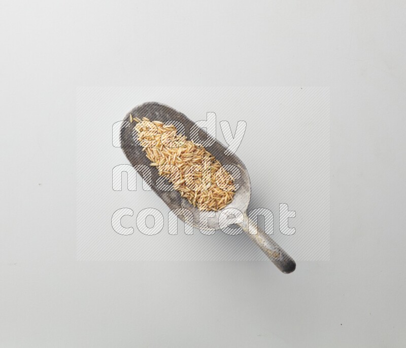 Top-view of a long grain brown rice, and shovel on white background
