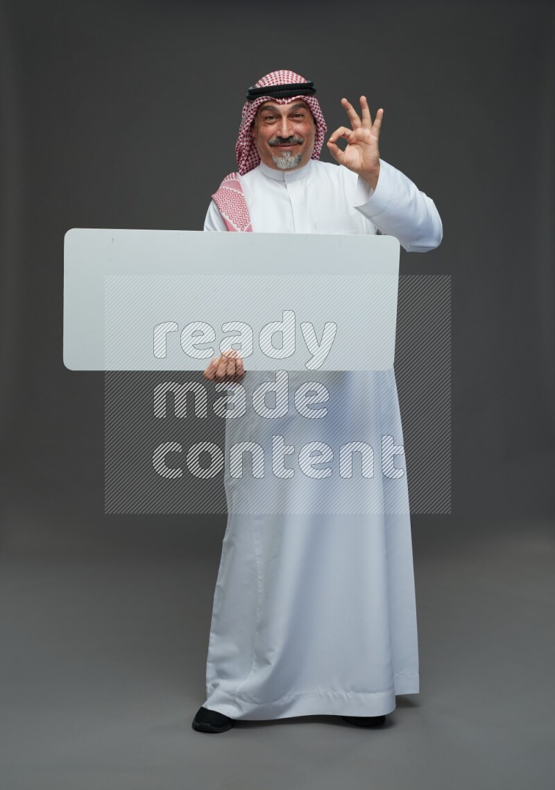 Saudi man with shomag Standing holding social media sing on gray background
