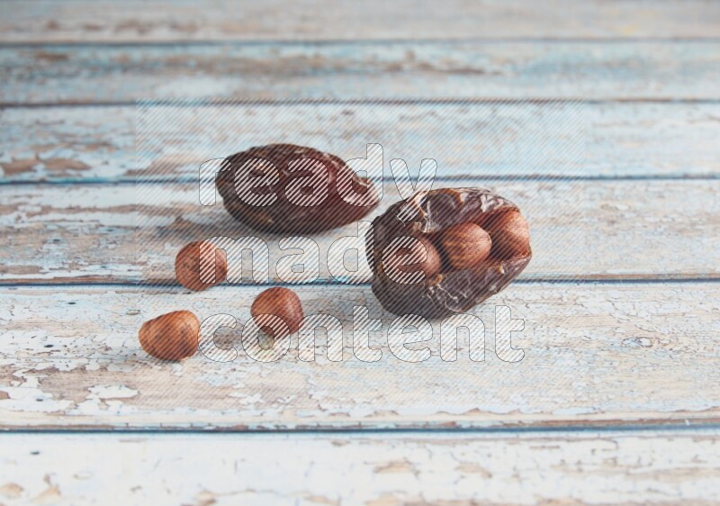 two hazelnuts stuffed madjoul dates on a light blue wooden background