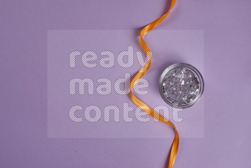 An orange collection of sewing and tailoring tools arranged on a purple background