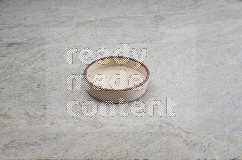 A beige pottery oven bowl on grey marble background
