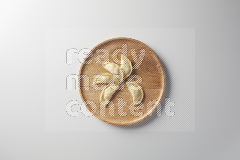 Five Sambosas on a wooden round plate on a white background