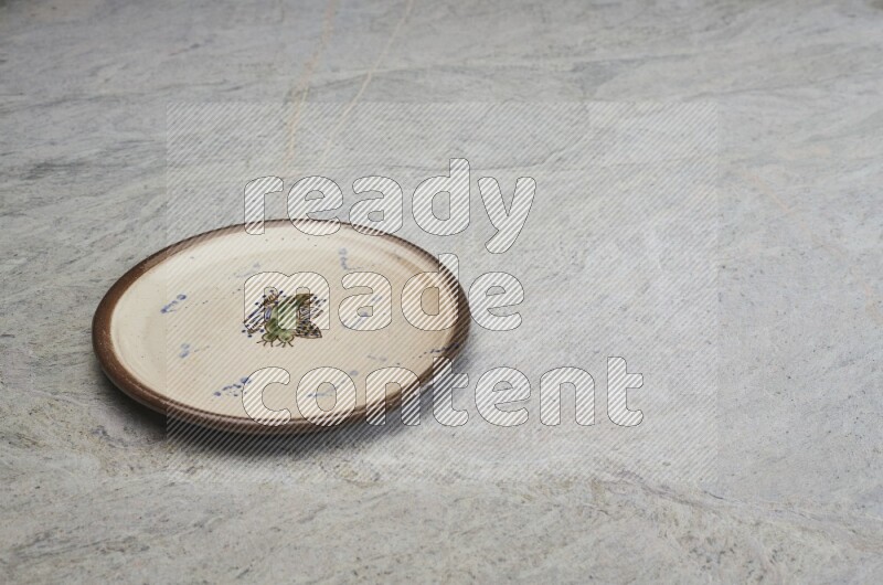 A decorative pottery plate on grey marble background