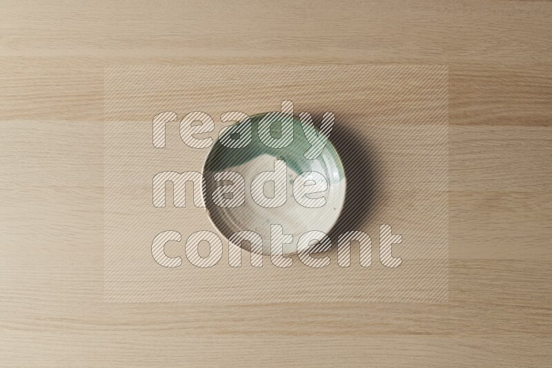 A multicolored pottery plate on light wooden background