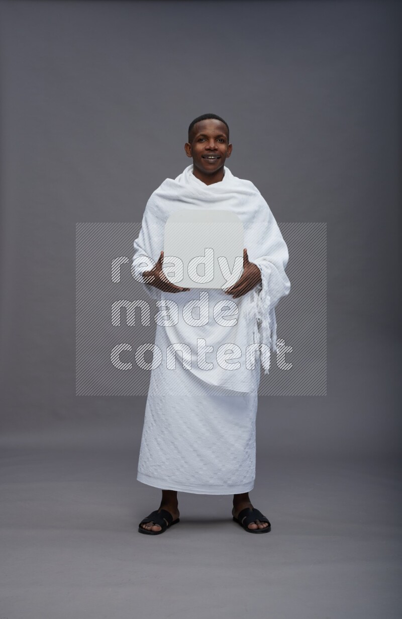 A man wearing Ehram Standing holding social media sign on gray background